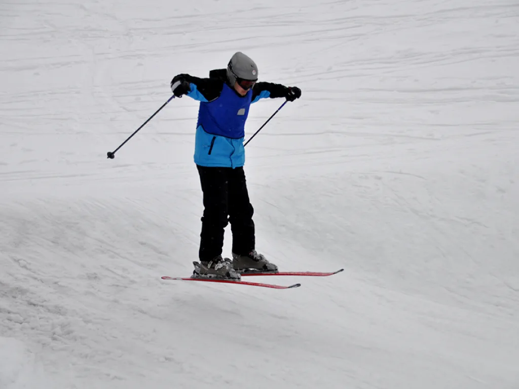 Skifahrer breitet beim Fahren die Arme aus.
